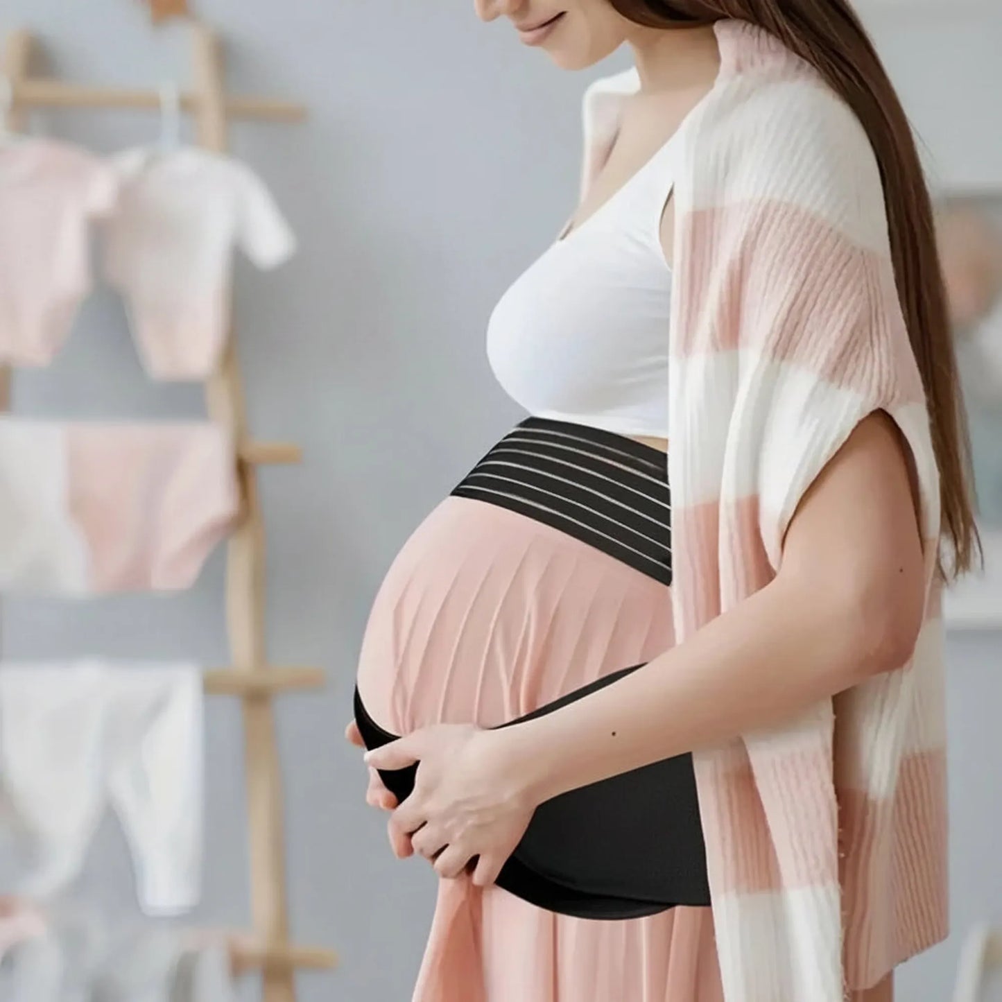 Pregnant woman wearing a pink and black adjustable maternity support belt for back and belly relief.