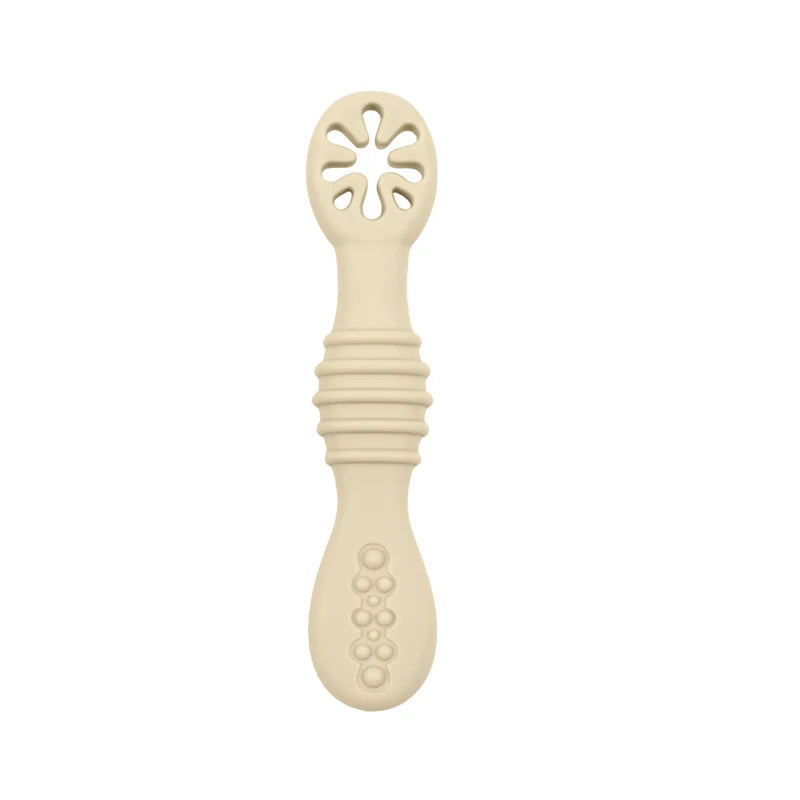 Beige silicone baby training spoon with textured handle and slotted head.