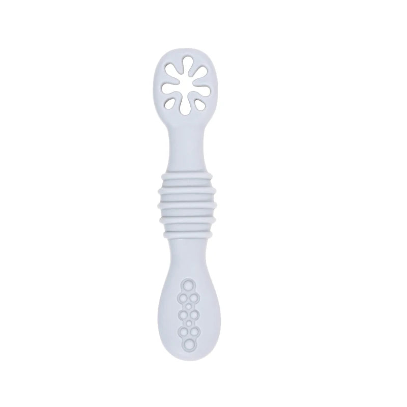 Soft grey silicone baby training spoon with textured handle and flower-shaped feeder.