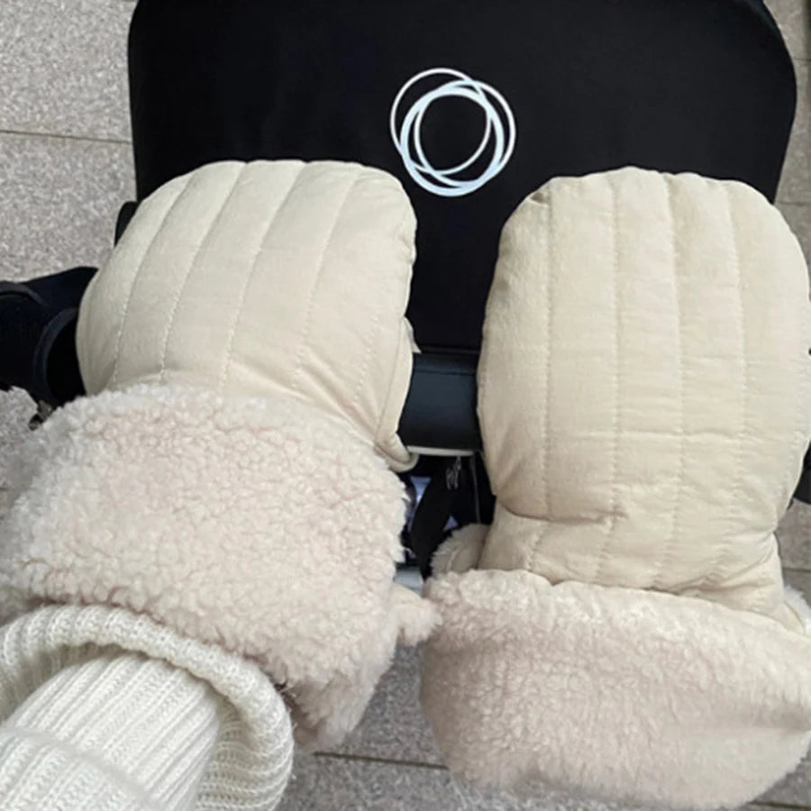 Cream-colored, windproof stroller mittens with soft fleece lining, attached to a black stroller handle.