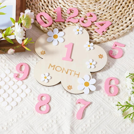 Wooden baby milestone cards with pink numbers and floral designs.