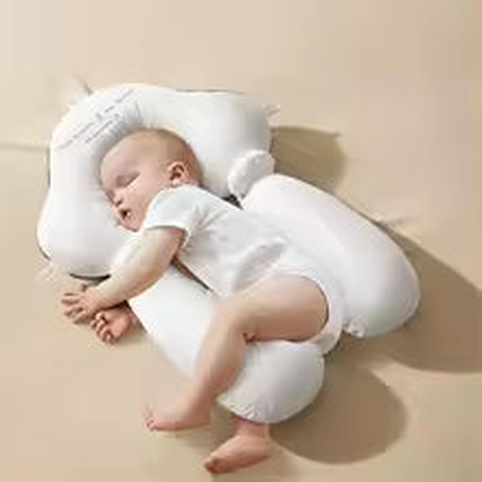 Sleeping baby on a white ergonomic newborn pillow with head and body support.