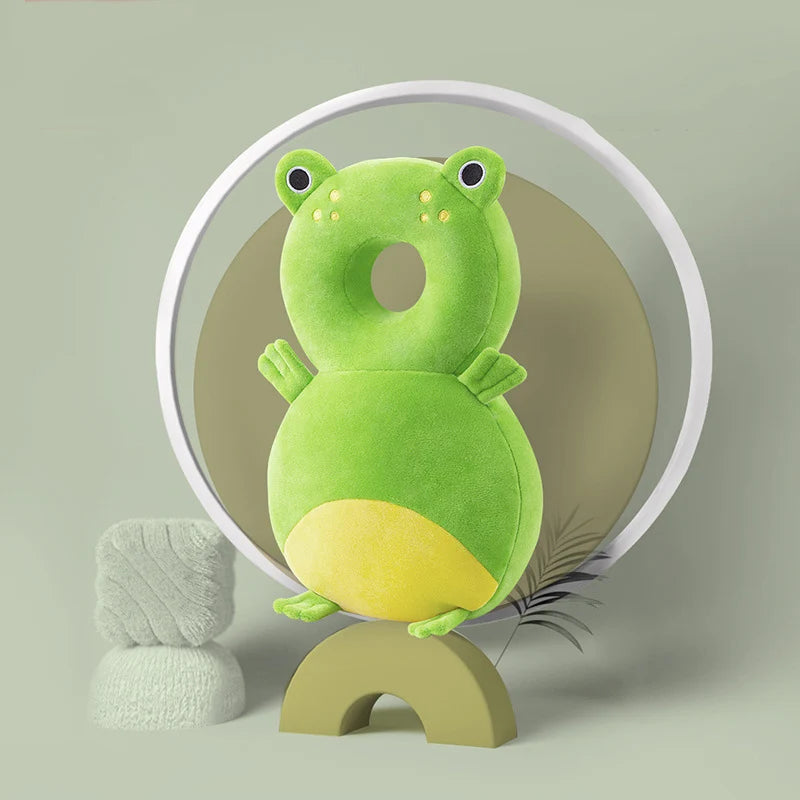 Green frog-shaped baby head protector cushion with yellow belly and spots, made of soft, breathable cotton.