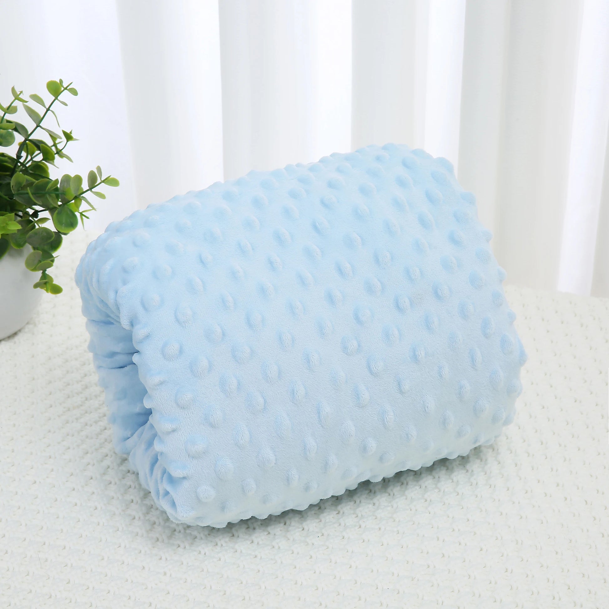 Soft blue ergonomic nursing arm pillow with textured dots for comfortable feeding.