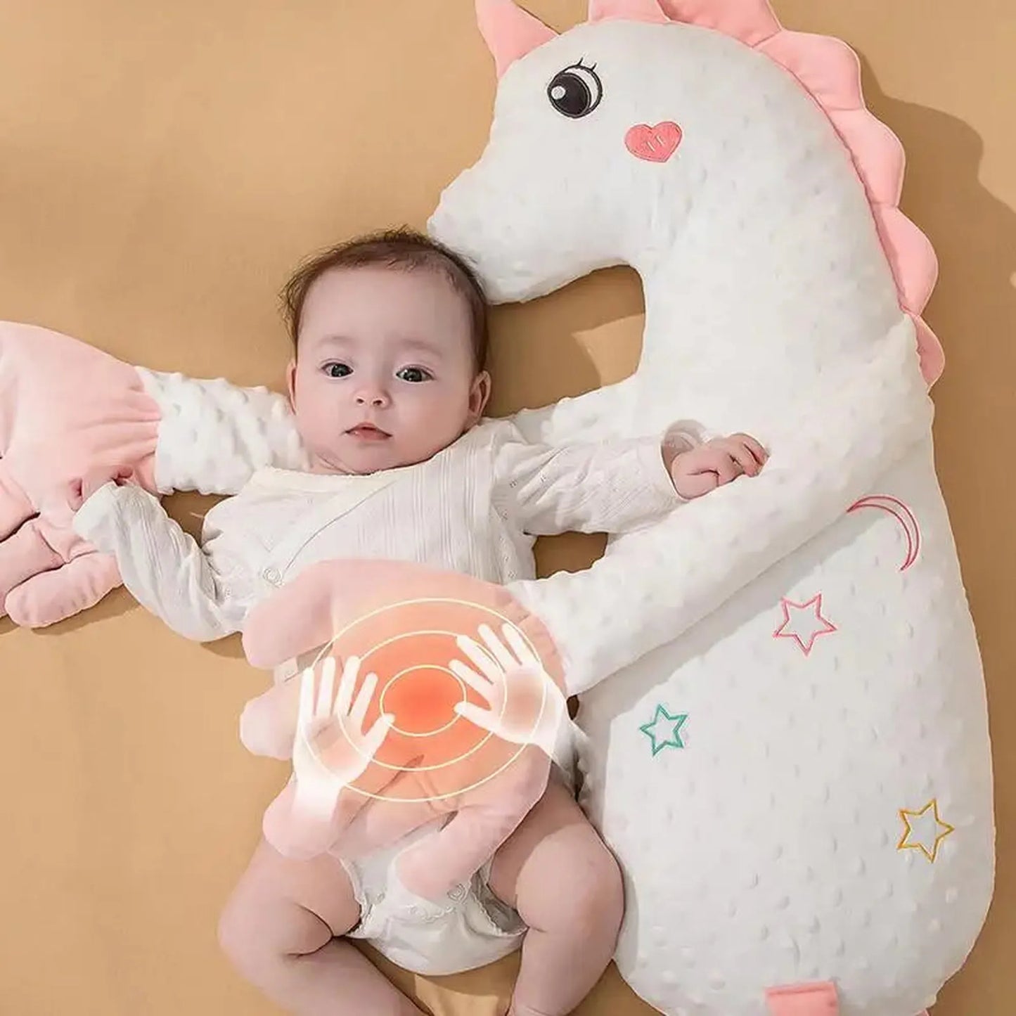 Baby with a white unicorn electric soothing pillow, featuring pink accents and a gentle tapping mechanism.