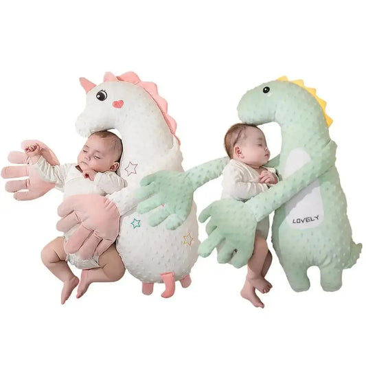 Two babies sleeping soundly, each hugged by a plush, electric soothing pillow: one white unicorn, one green dinosaur.