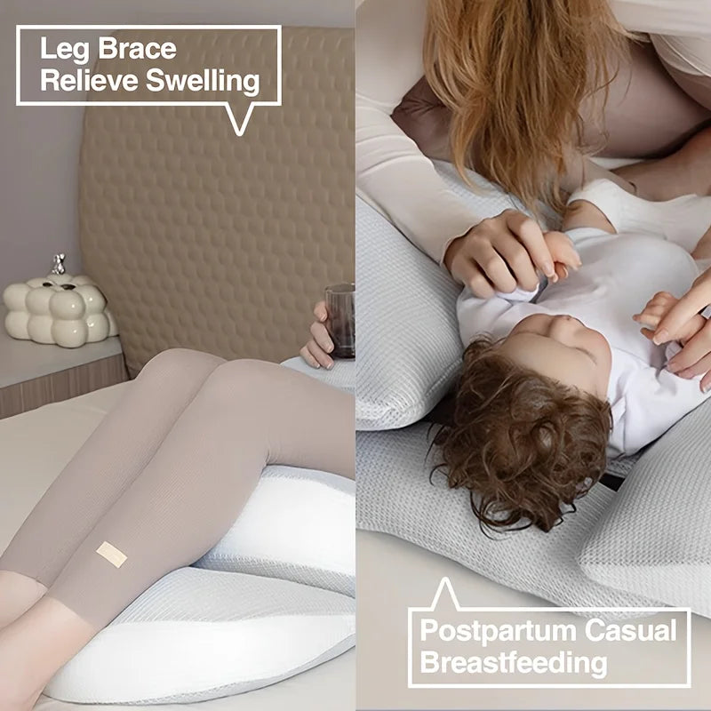 Gray U-shaped pregnancy pillow supporting a woman's legs and a baby for postpartum breastfeeding.