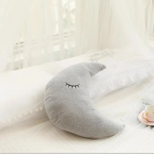 Soft gray crescent moon pillow with embroidered sleeping eyes, ideal for nursery decor.