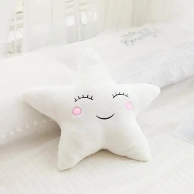 Soft white star-shaped baby decorative pillow with embroidered sleepy eyes and pink cheeks.