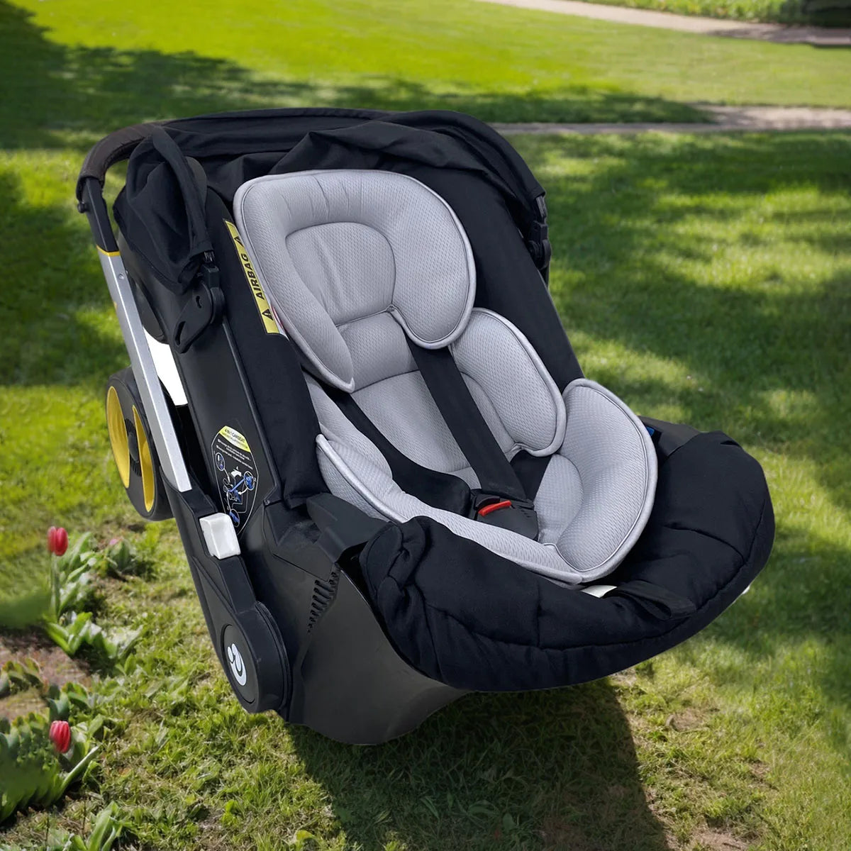 Gray universal baby stroller and car seat support cushion in a black car seat.