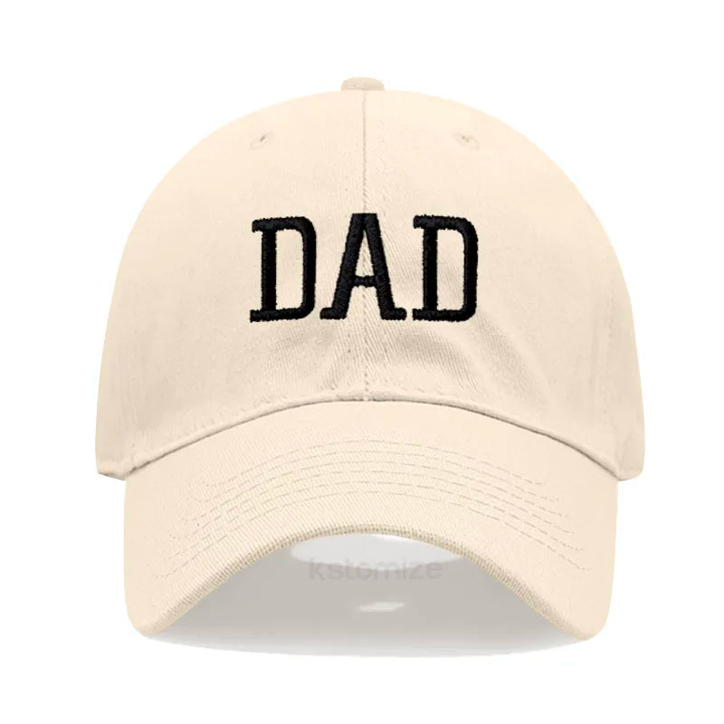 Adjustable beige cotton baseball cap with "DAD" embroidered in black.