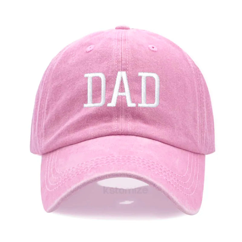 Pink cotton baseball cap with "DAD" embroidered in white, adjustable fit.