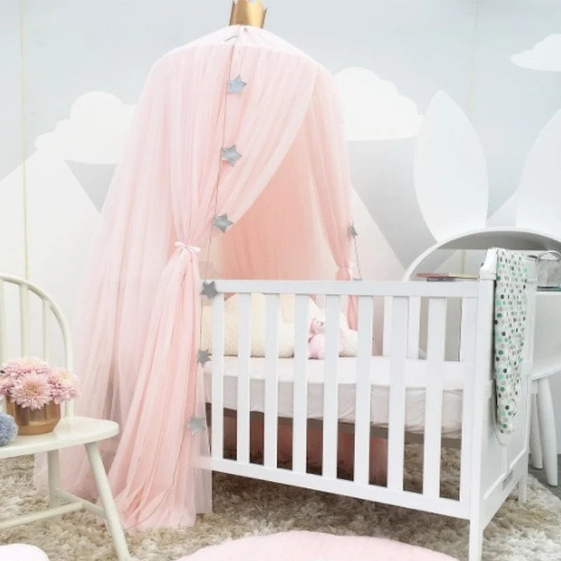 Pink tulle baby crib canopy with star decorations and a gold crown top.