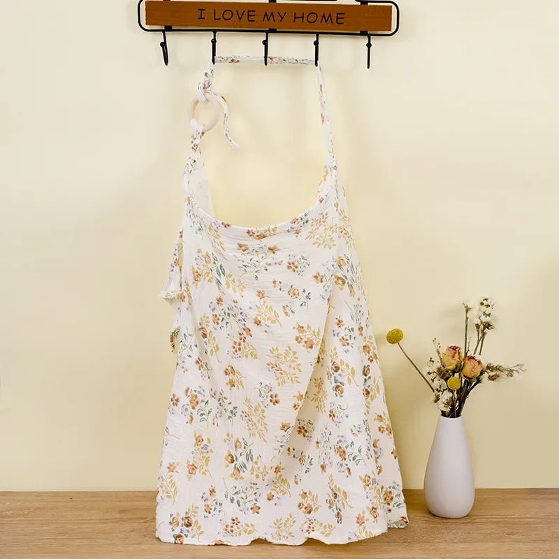 White cotton nursing cover with a delicate floral print, hanging from a hook.