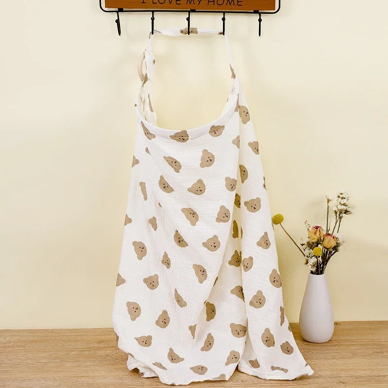 White cotton nursing cover with brown bear print, adjustable strap, also usable as a stroller blanket.