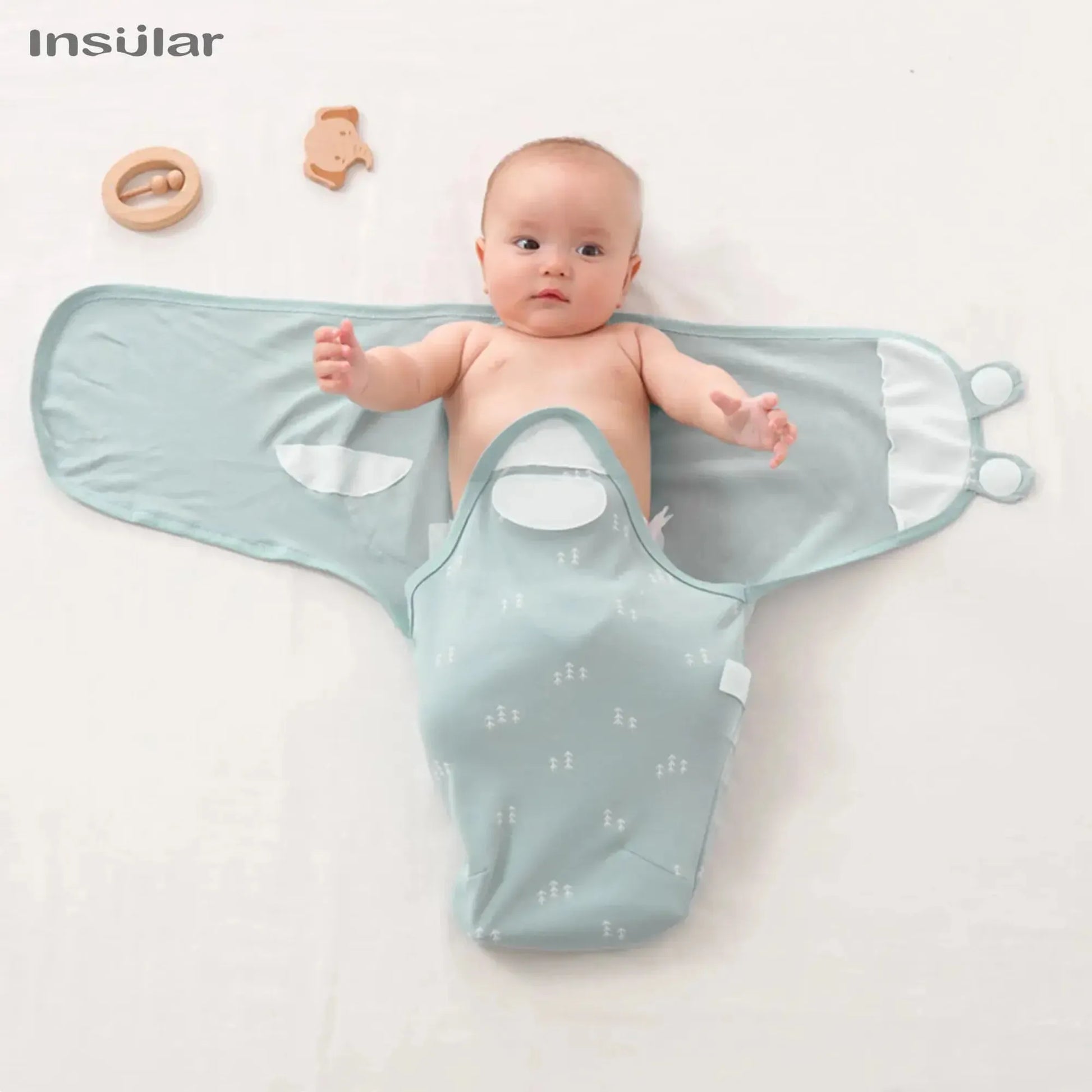 Baby swaddle in light blue with white tree pattern, open with infant inside, 100% cotton.