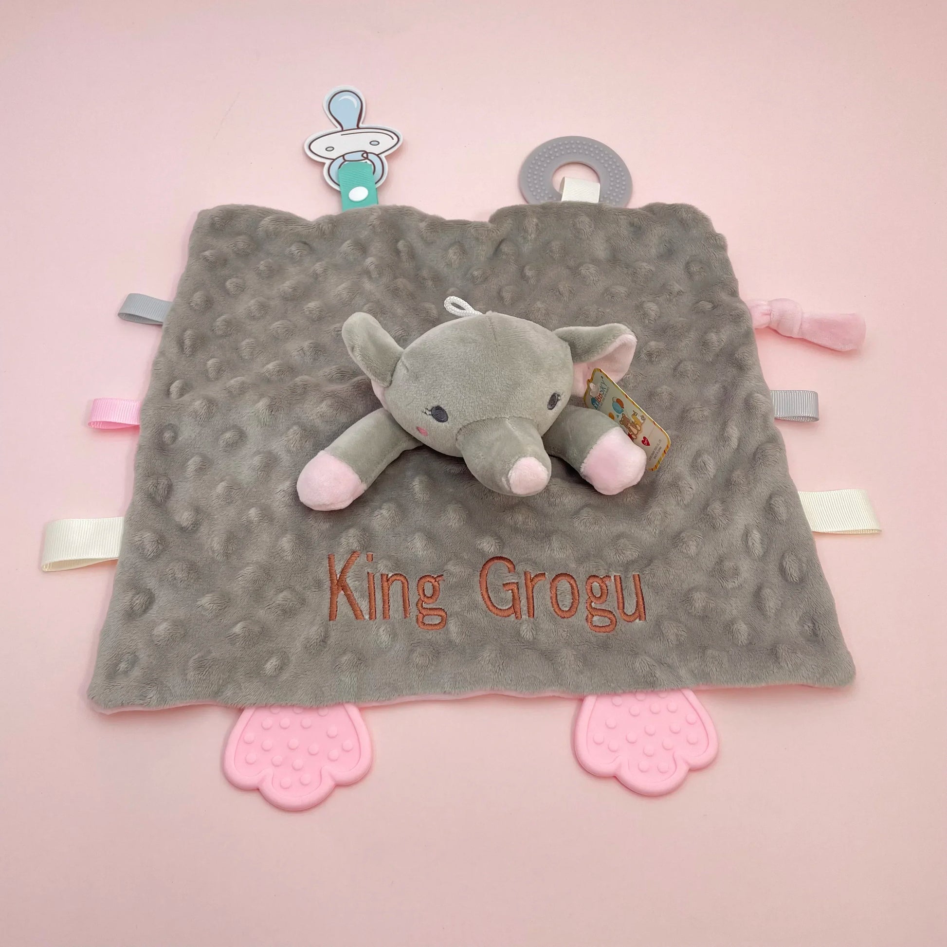 Gray minky baby security blanket with an elephant plush, pink silicone teether feet, and personalized "King Grogu" embroidery.
