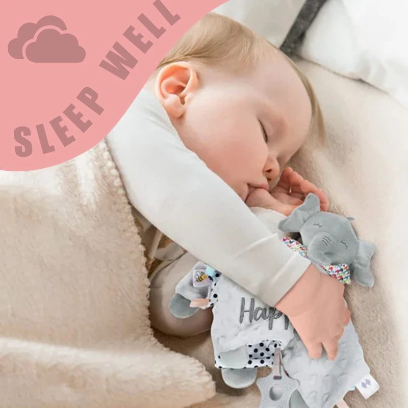 Baby sleeping peacefully, hugging a soft gray elephant security blanket with a teether and "Happy" embroidery.