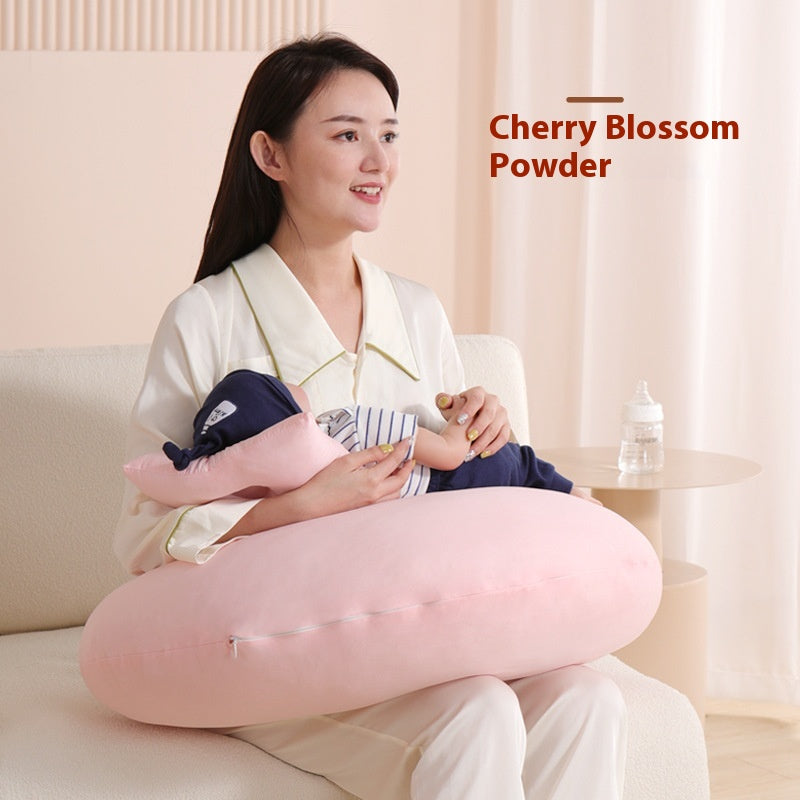 Woman holding a baby on a soft, pink, multi-functional nursing pillow.