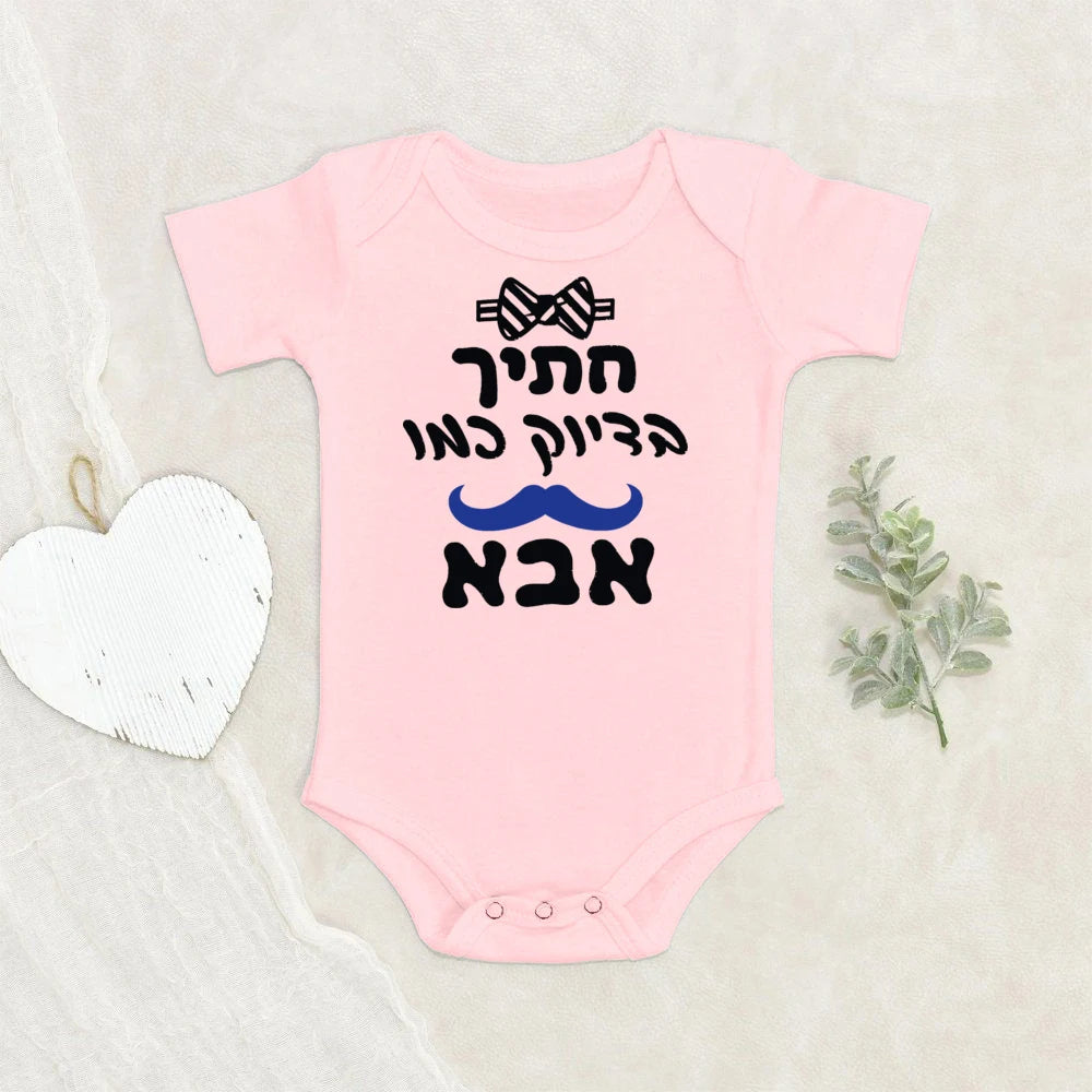 Pink short-sleeve baby bodysuit with "Handsome like Dad" text, black bow tie, and blue mustache graphic.