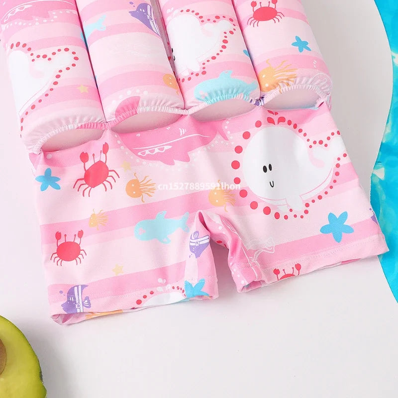 Pink kids' floatation swimsuit with colorful cartoon sea animal prints, perfect for pool or beach.
