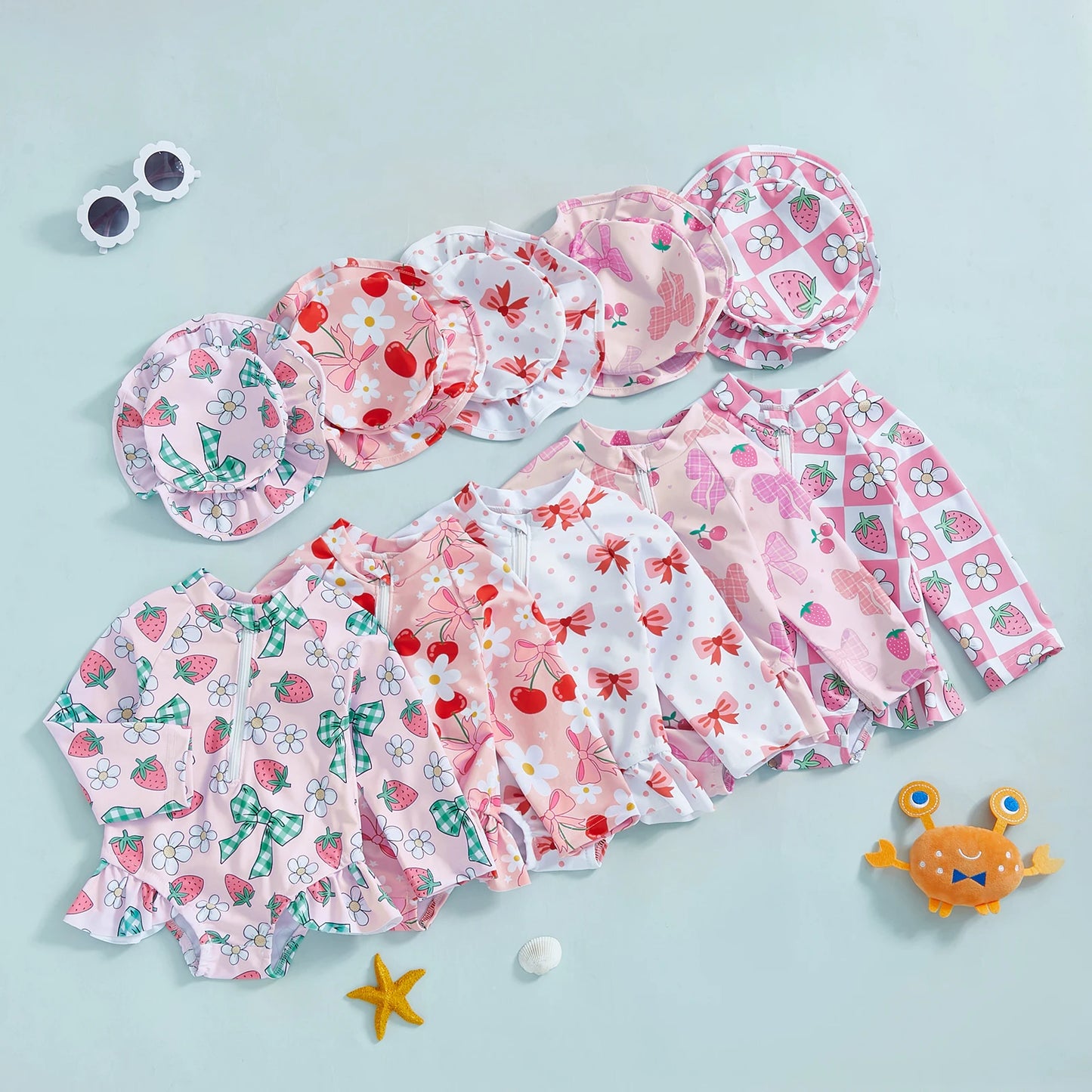 Infant long-sleeve rashguard swimsuits with matching hats in various pink floral and fruit prints.