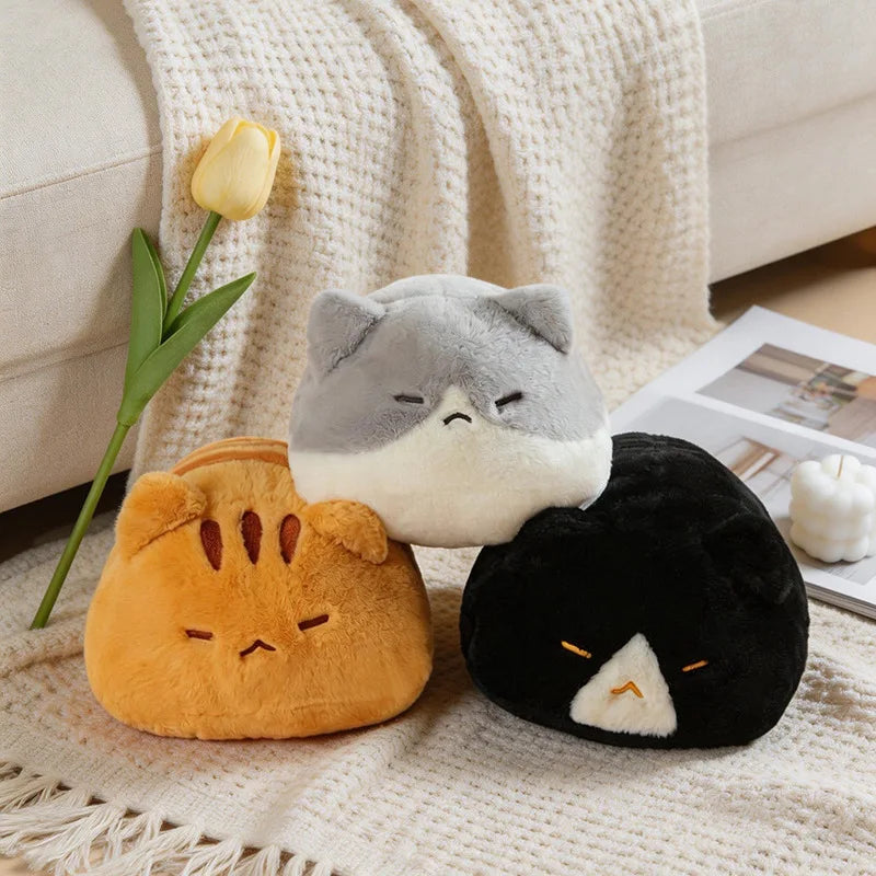 Three soft, plush cat pillows in orange, gray, and black, 45cm, on a cozy blanket.