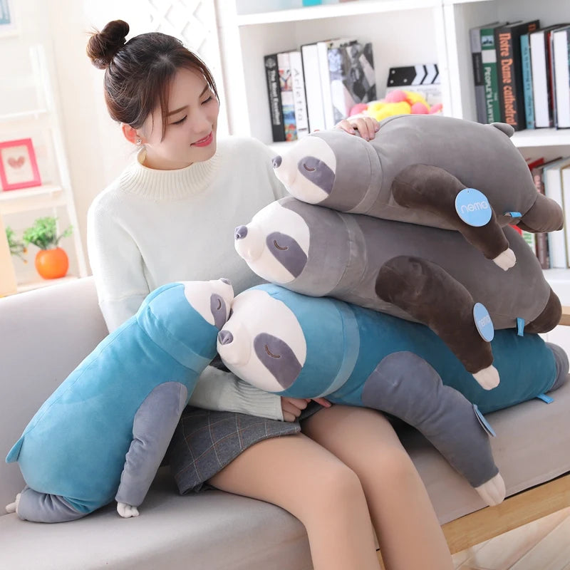 Woman holding three soft plush sloth toys in blue and gray, varying sizes.