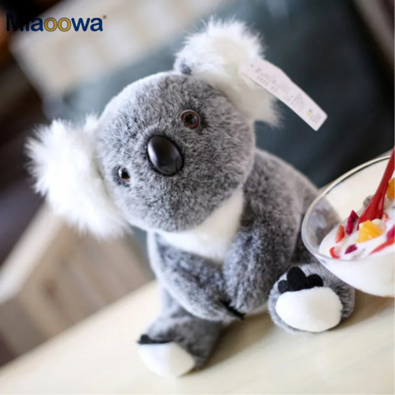 Soft gray plush koala toy with white ears and black nose, 13cm or 17cm, sitting next to a dessert.