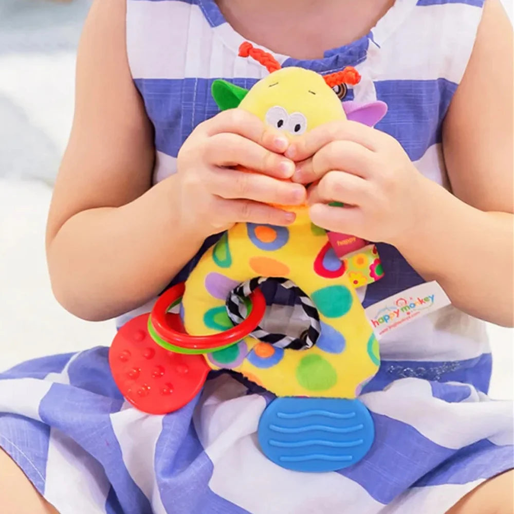 Soft yellow plush animal rattle teether toy with colorful polka dots, held by a child.