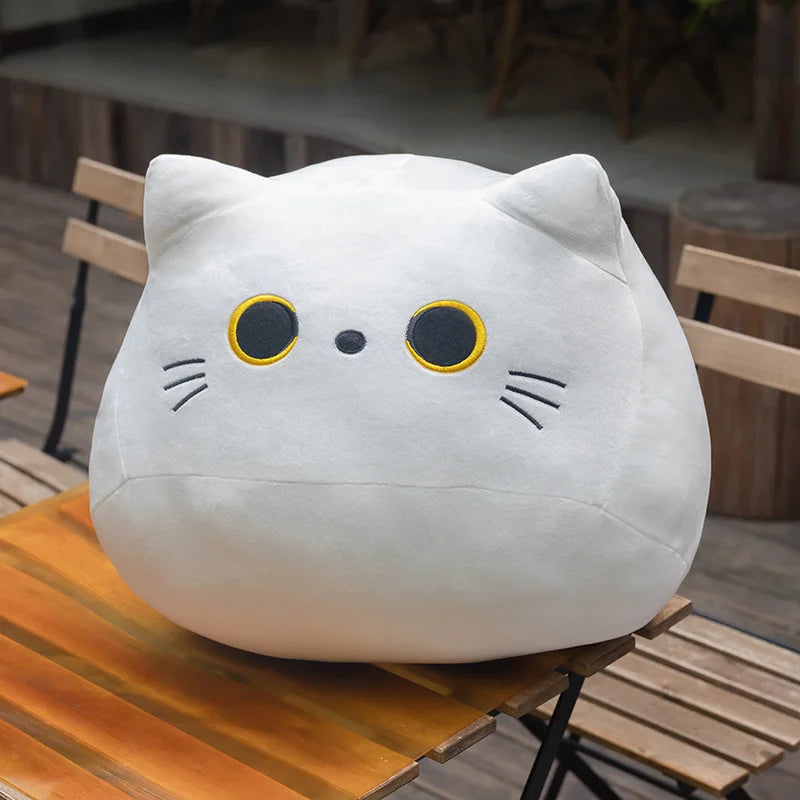 Soft white plush cat pillow with embroidered yellow eyes and whiskers.