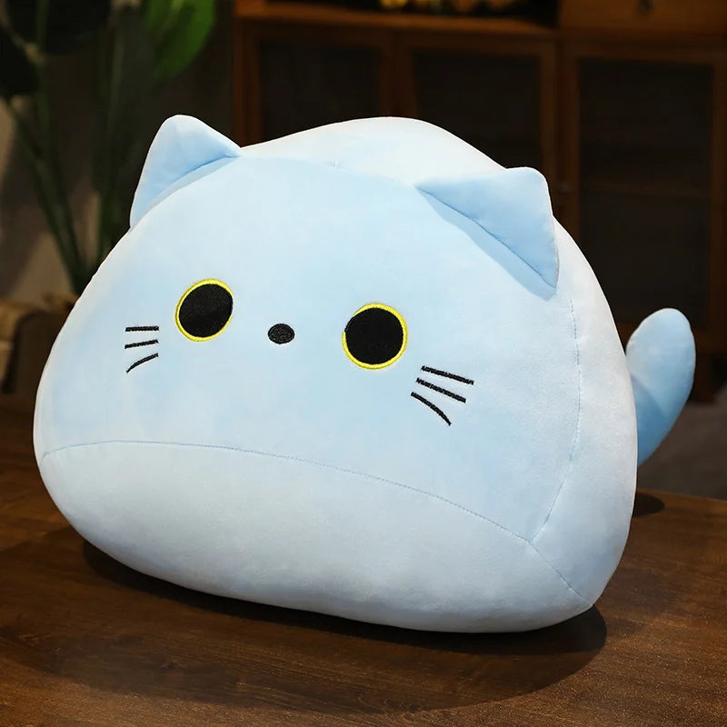 Soft blue plush cat toy with embroidered eyes, nose, and whiskers, sitting on a wooden surface.