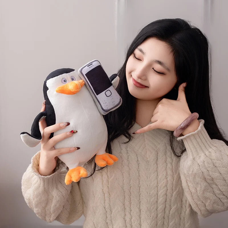 Soft 28cm Madagascar plush penguin toy holding a phone, with a woman making a call gesture.