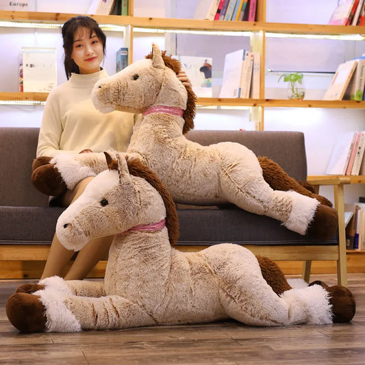 Two large, soft brown plush horse toys with pink collars, one held by a woman on a sofa.