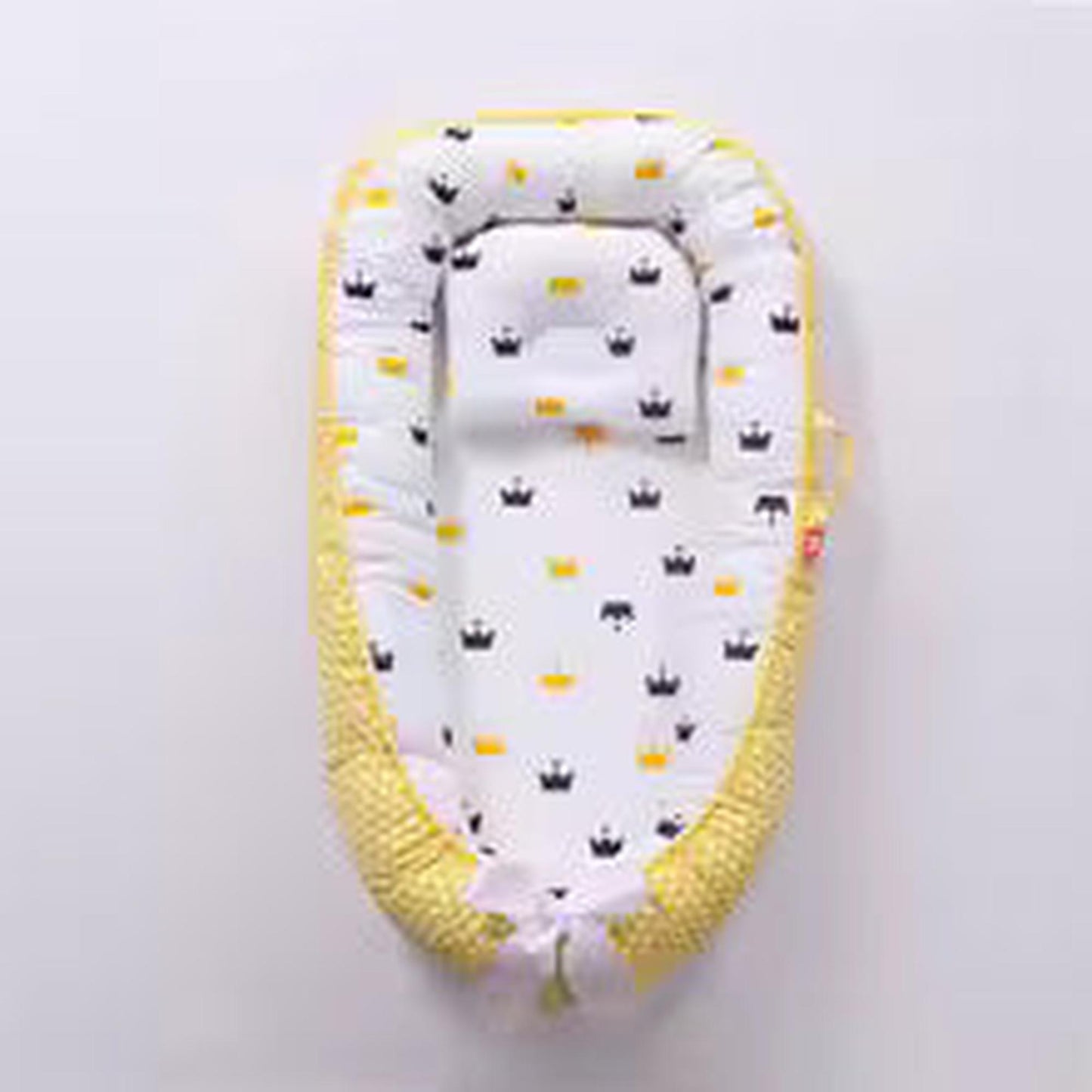 Adjustable yellow baby nest with white crown print, soft cotton, and head support.