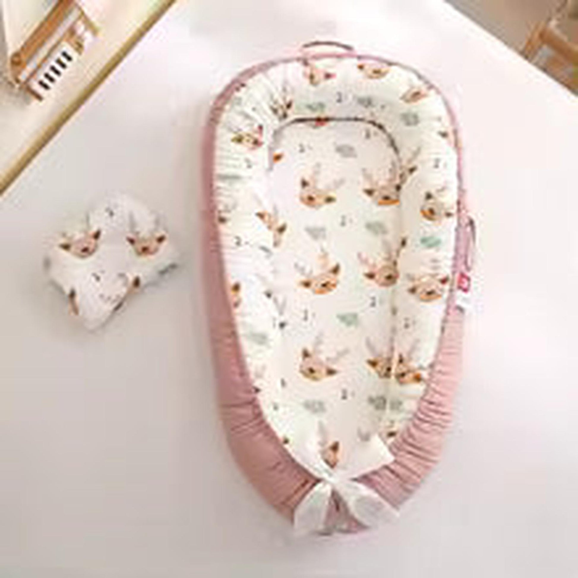 Pink baby nest with deer print, breathable cotton, adjustable, and portable.