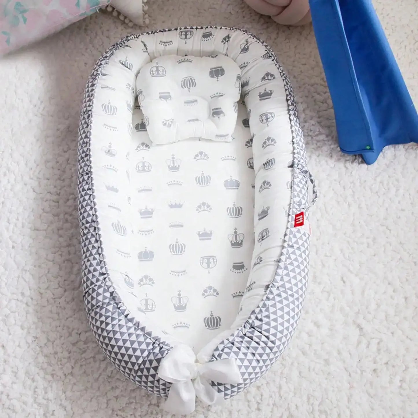 Breathable baby nest with gray geometric and crown patterns, adjustable design, and soft cotton fabric.