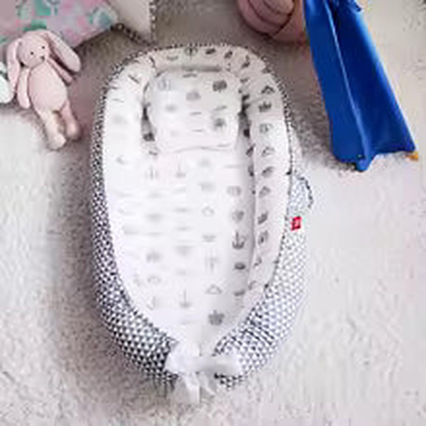Adjustable baby nest in white and gray geometric print with a soft pillow.
