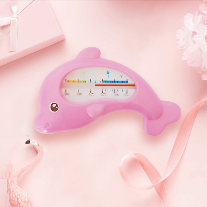 Pink dolphin-shaped baby bath water thermometer with a clear temperature scale, on a soft pink background.