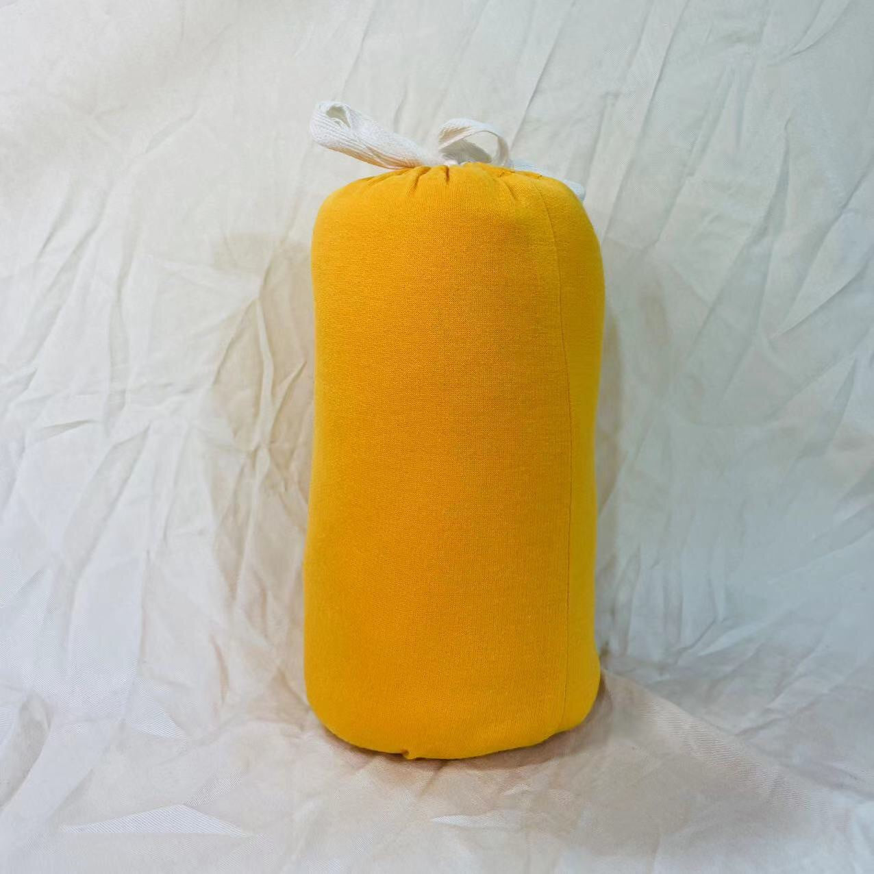 Rolled yellow soft cotton baby wrap carrier with white ties, ready for storage or travel.