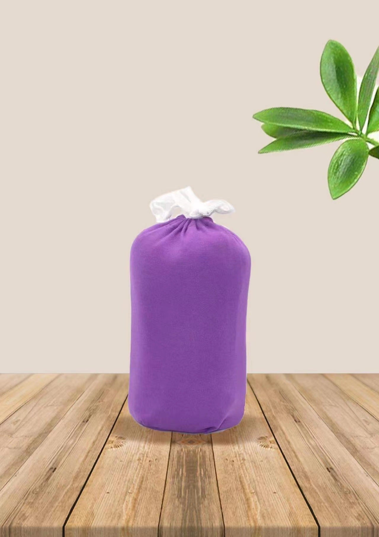 Purple soft ergonomic baby wrap carrier, tied with a white ribbon, on a wooden surface.