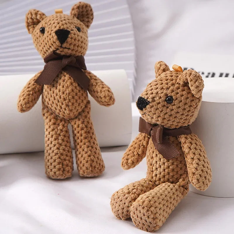 Two small, brown crocheted teddy bears with dark brown bows, one standing and one sitting.