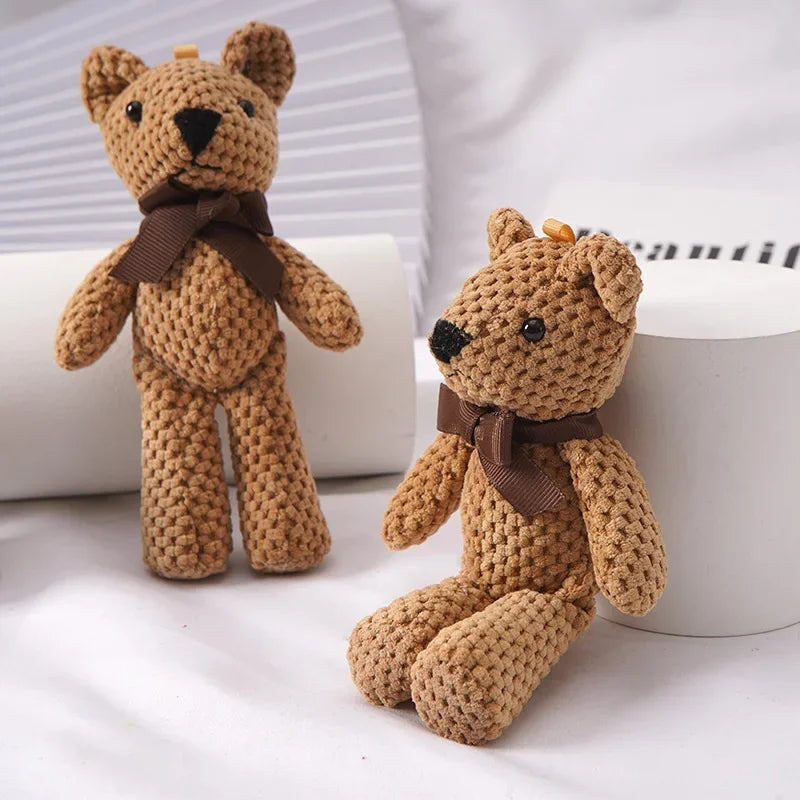 Two small, brown crocheted teddy bears with dark brown bows, one standing and one sitting.