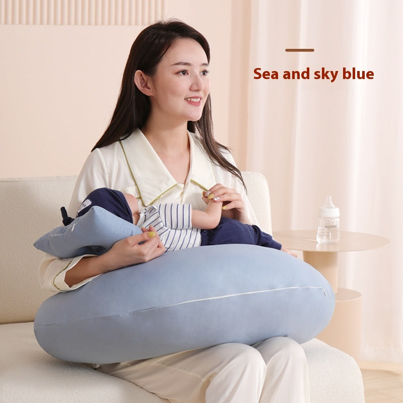 Smiling mother holding a baby on a light blue multi-functional nursing pillow, with a bottle nearby.