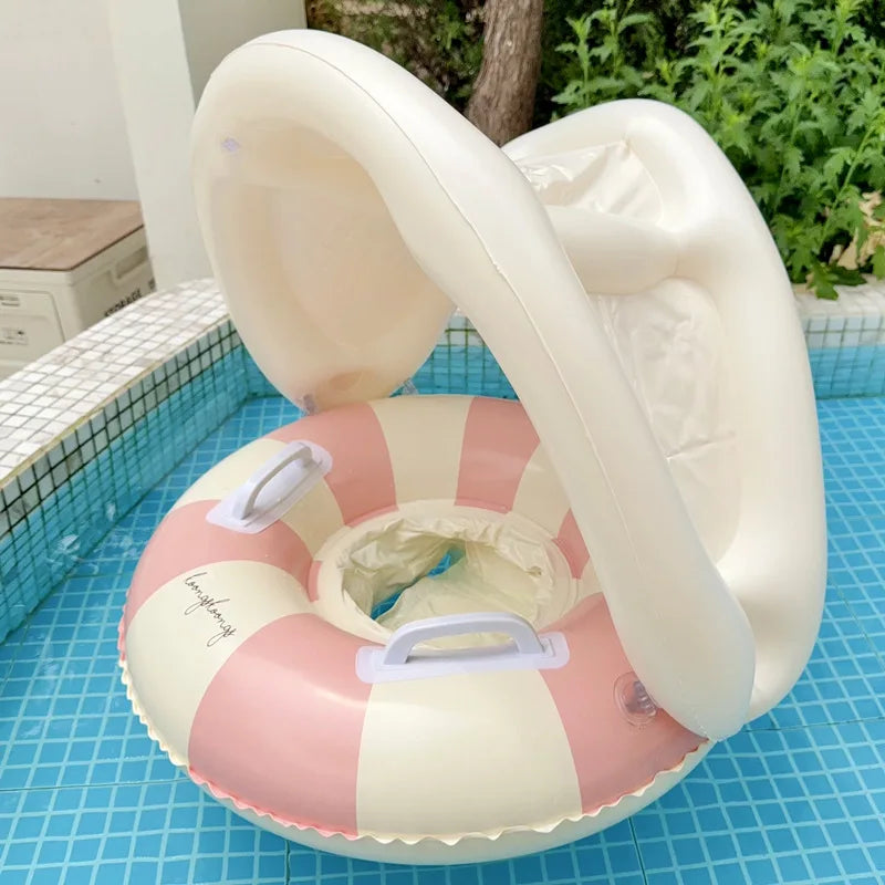 Pink and white striped inflatable baby swim float with a removable sun canopy and handles, in a blue tiled pool.