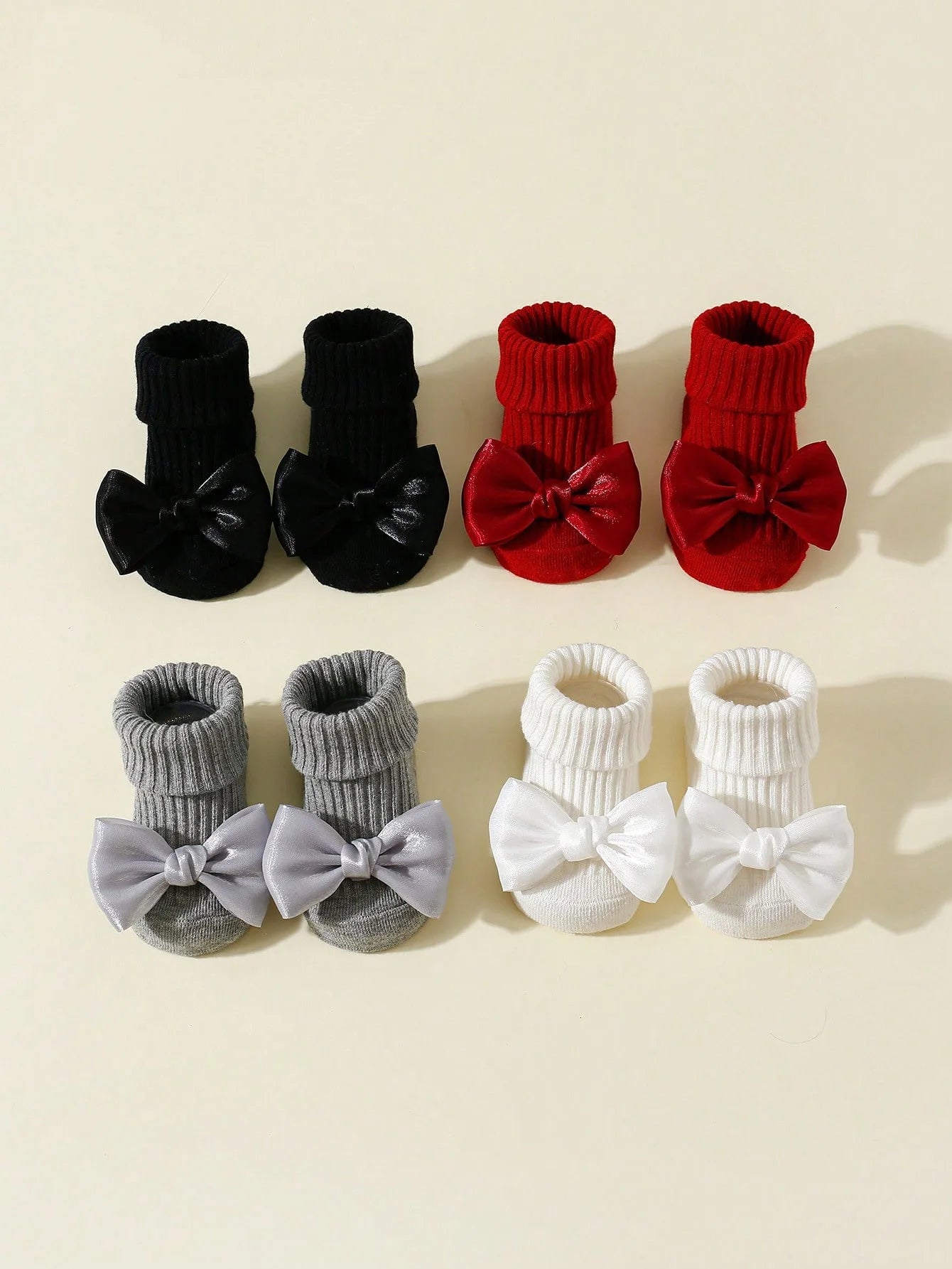 Four pairs of anti-slip baby socks with bows: black, red, gray, and white cotton.