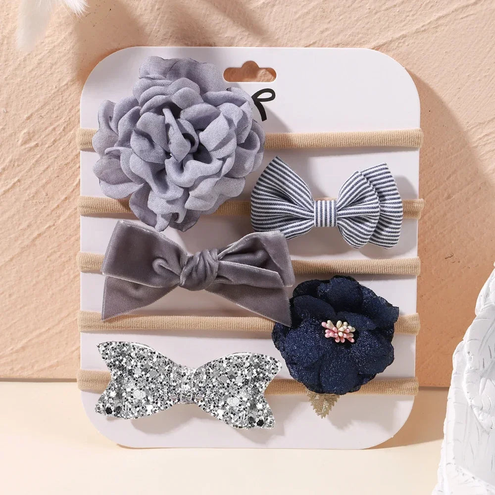 Set of 5 baby headbands: gray floral, striped bow, velvet bow, navy lace flower, and silver glitter bow.