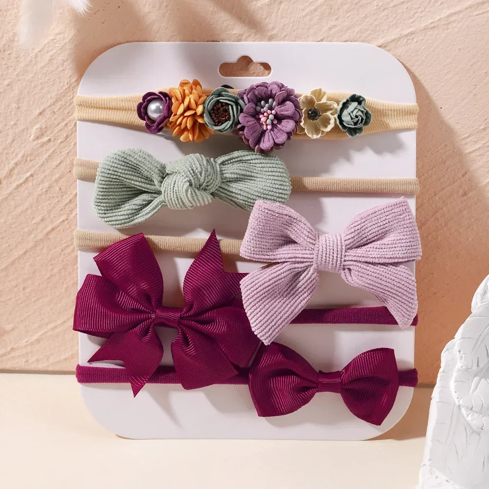 Set of 5 baby headbands with floral lace and ribbed bows in sage, lavender, and burgundy.