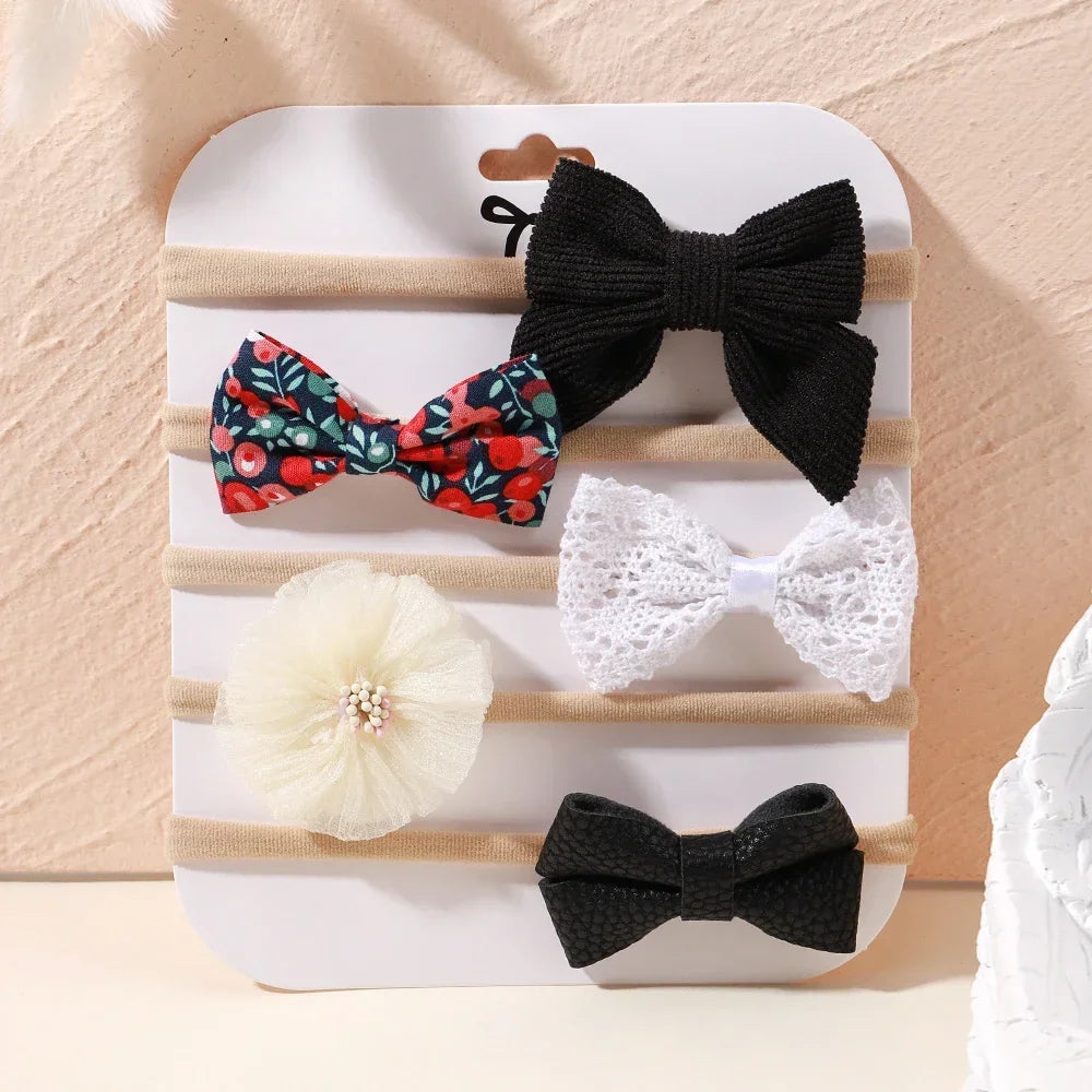 Set of 5 baby headbands with lace flowers and bows in black, white, and floral patterns.