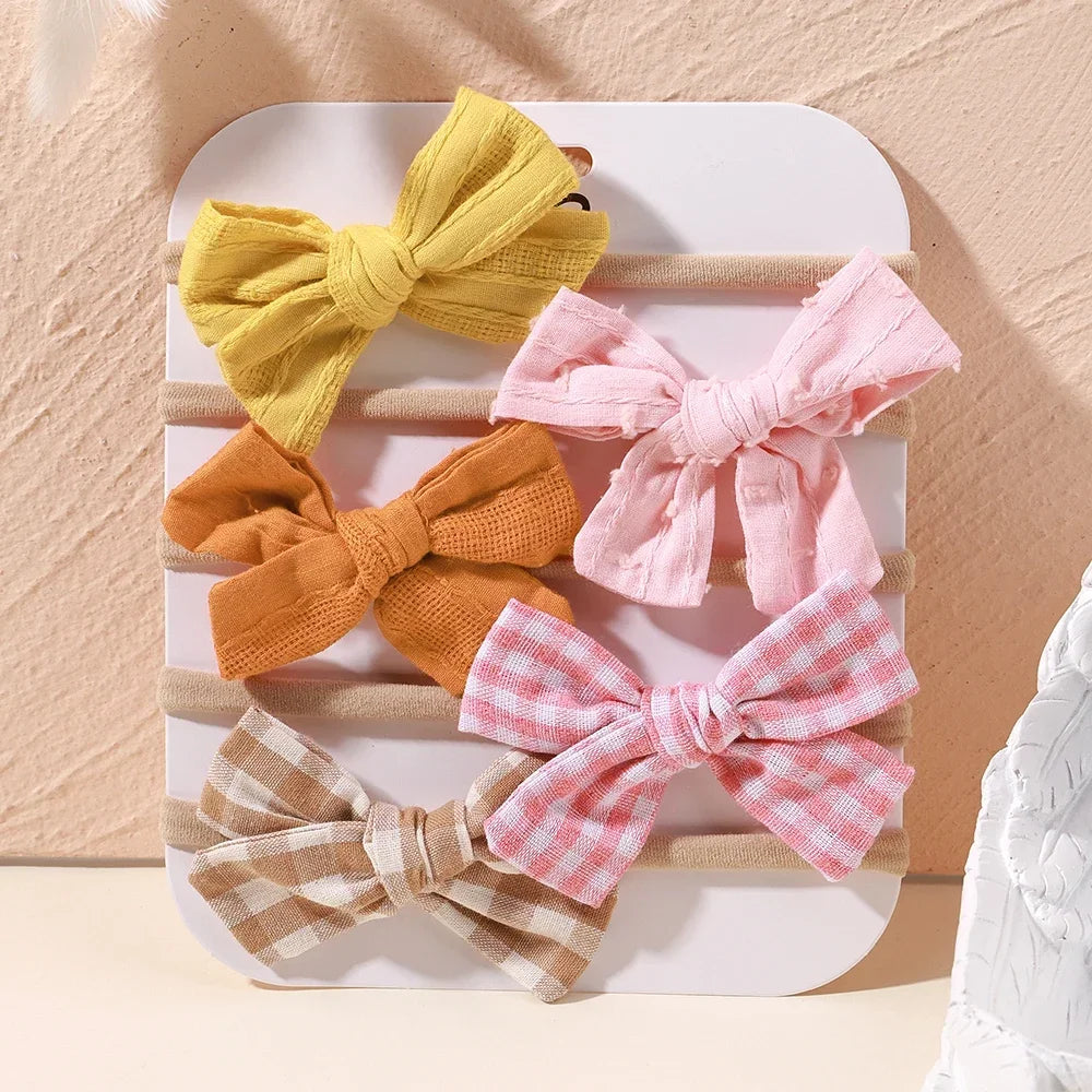 Set of 5 baby headbands with soft fabric bows in yellow, pink, orange, and plaid designs.